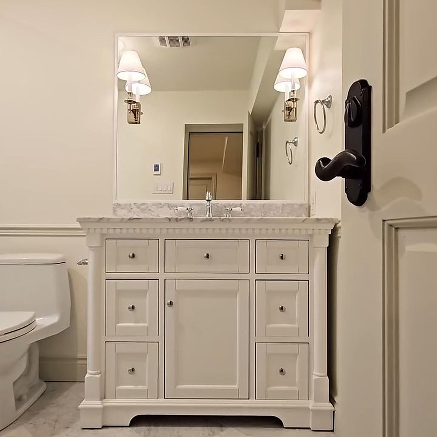 Le même espace après les travaux : une salle de bain avec vanité blanche et toilette