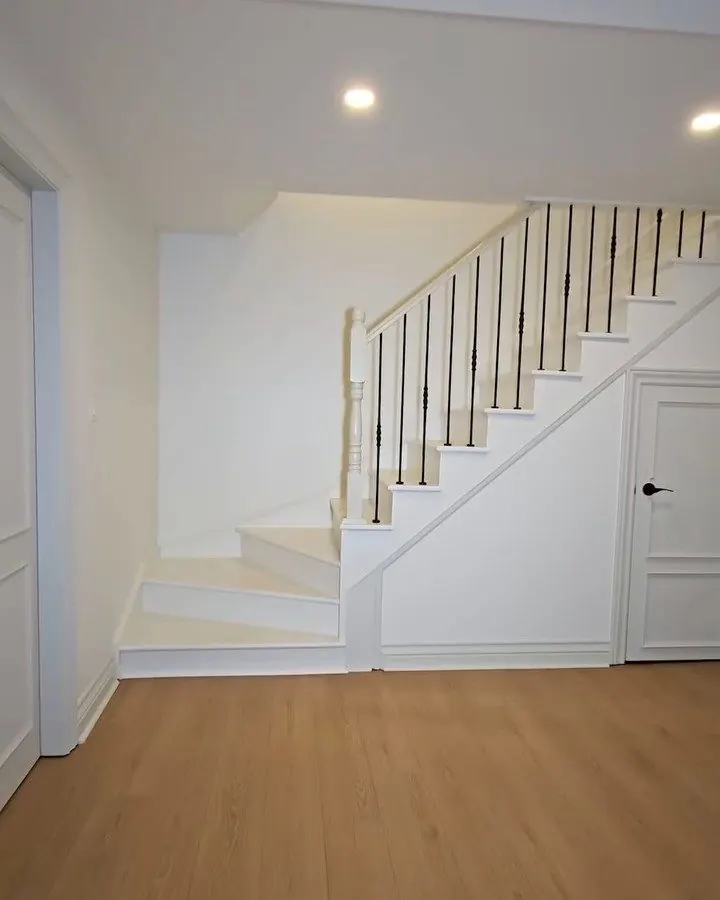 Escalier de sous-sol avec rampe blanche et barreaux noirs